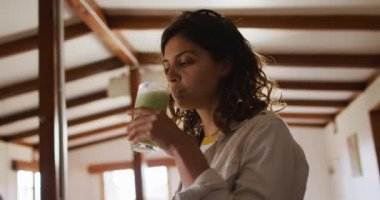 Mutlu melez kadın, kır evinde oturmuş gülümsüyor ve sağlık içeceği içiyor. Sağlıklı yaşam, doğaya yakın kırsal kesimde ev.