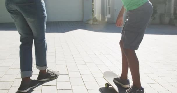 アフリカ系アメリカ人の父親は フロントヤードでスケートボードに息子を教える 父親と愛の概念 — ストック動画