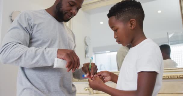 アフリカ系アメリカ人の父親は息子の歯ブラシを自宅の浴室に置いていた 父親と愛の概念 — ストック動画