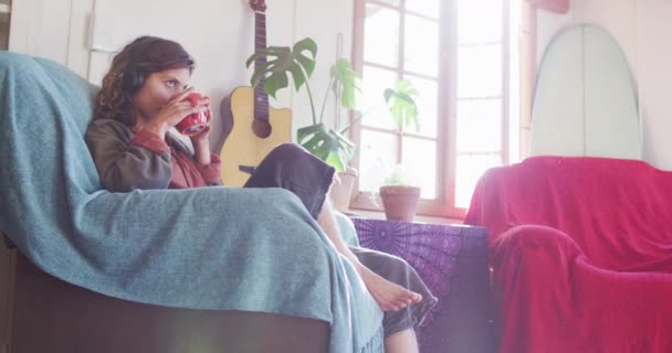 Relaxado Mulher Raça Mista Usando Fones Ouvido Sentado Bebendo Chá — Vídeo de Stock