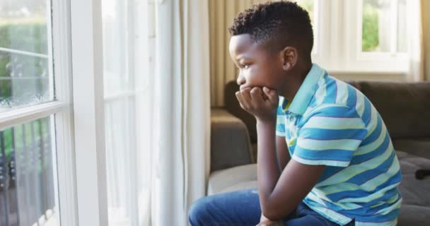 Niño Afroamericano Estresado Mirando Por Ventana Mientras Está Sentado Sofá — Vídeos de Stock