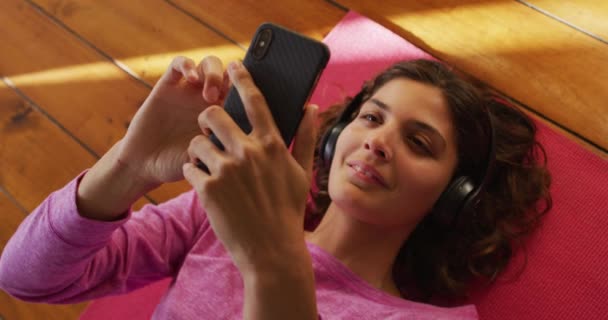 Happy Mixed Race Woman Headphone Lying Yoga Mat Using Smartphone — Stok Video