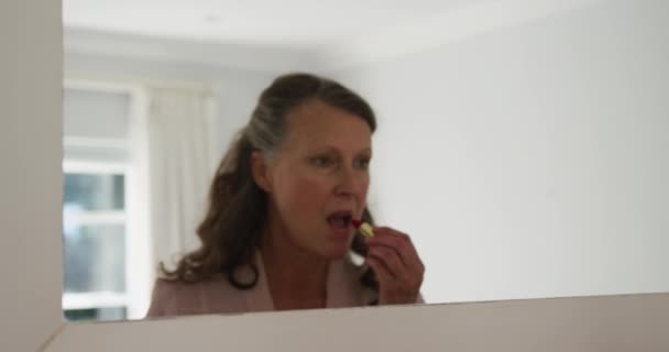Starsza Biała Kobieta Stojąca Pokoju Patrząca Lustro Nakładająca Szminkę Domu — Wideo stockowe