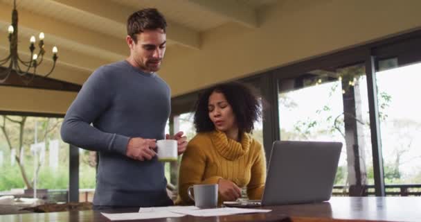 Diversa Pareja Hablando Sala Estar Utilizando Ordenador Portátil Mirando Papeleo — Vídeos de Stock