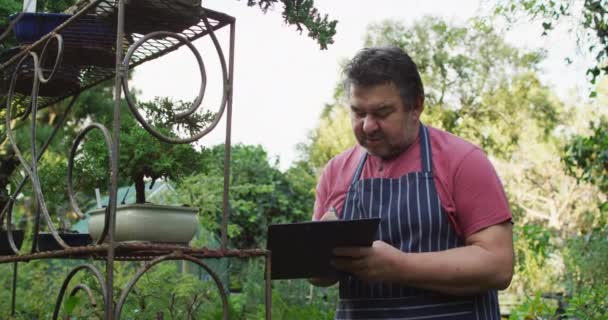 Vit Manlig Trädgårdsmästare Gör Anteckningar Trädgården Centrum Arbetar Bonsai Plantskola — Stockvideo