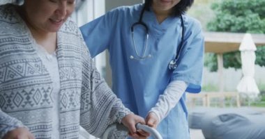 Gülümseyen Asyalı kadın doktor mutlu kadın hastaya hastanede yürüyen çerçeveyle yardım ediyor. ilaç, sağlık ve sağlık hizmetleri.