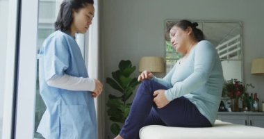 Asyalı kadın fizyoterapist ameliyatta dizleri ağrıyan kadın hastayı tedavi ediyor. fizyoterapi, sağlık ve sağlık hizmetleri.