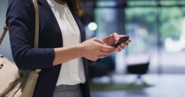 Modern ofiste akıllı telefon kullanan, kahverengi saçlı, beyaz bir iş kadını. İş ve iş adamları ofis kavramında.