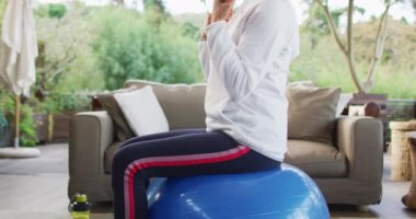 Kıdemli melez kadın antrenman yapıyor, dambılları kaldırıyor. emeklilik ve yaşlılık hayatı, evde yalnız zaman geçirmek..