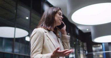 Kafkasyalı iş kadını modern ofisin lobisinde akıllı telefondan konuşuyor. İş ve iş adamları ofis kavramında.