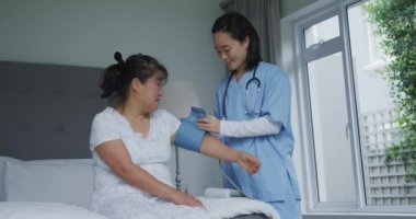 Gülümseyen Asyalı kadın doktor hastanedeki mutlu kadın hastanın kan basıncını ölçüyor. ilaç, sağlık ve sağlık hizmetleri.