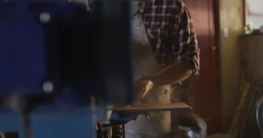 Kafkas erkek bıçak imalatçısı atölyede gözlüklü ve zımpara makinesi kullanıyor. Bağımsız küçük işletmeci iş başında.