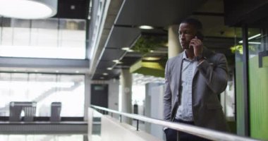 Modern ofiste koridorda akıllı telefondan konuşan Afrikalı Amerikalı iş adamı. İş ve iş adamları ofis kavramında.
