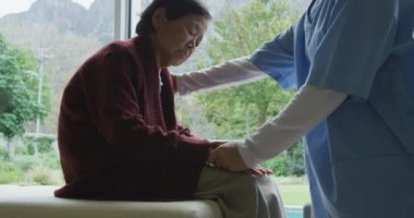 Gülümseyen Asyalı kadın doktor yaşlı kadın hastayı rahatlatıyor ve ameliyatta konuşuyor. fizyoterapi, sağlık ve sağlık hizmetleri.