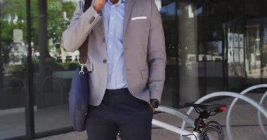 Modern ofis binasının dışında akıllı telefondan konuşan Afrikalı Amerikalı iş adamı. İş ve iş adamları ofis kavramında.