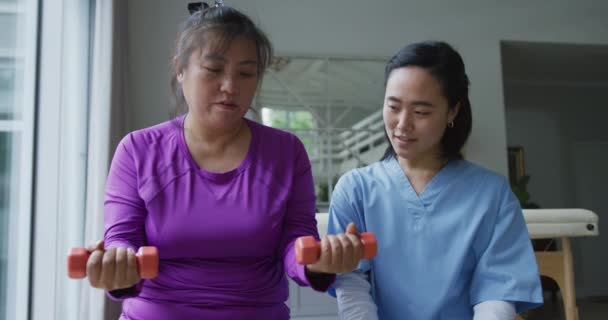 Fisioterapeuta Asiática Ajudando Paciente Feminino Exercitar Braços Com Halteres Momento — Vídeo de Stock