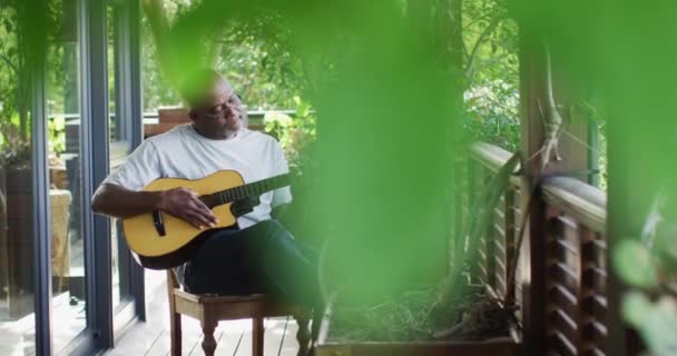 Homem Idoso Afro Americano Pensativo Sentado Varanda Tocando Guitarra Acústica — Vídeo de Stock