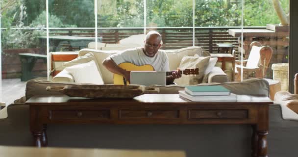 Χαρούμενος Αφροαμερικάνος Τελειόφοιτος Στο Σαλόνι Παίζει Ακουστική Κιθάρα Και Χρησιμοποιεί — Αρχείο Βίντεο