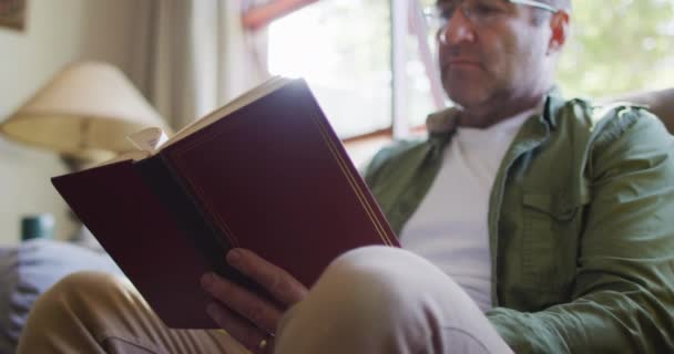 Vit Man Sitter Soffan Och Läser Bok Hemma Hushållsliv Och — Stockvideo