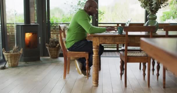 Hombre Mayor Afroamericano Sentado Mesa Comedor Trabajando Usando Portátil Estilo — Vídeo de stock