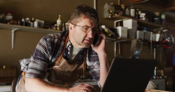 Konzentrierter Kaukasischer Messermacher Der Werkstatt Mit Laptop Und Smartphone Unabhängiger — Stockvideo