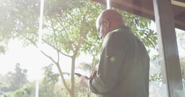 富有洞察力的非洲裔美国老人坐在阳台上 在阳光下使用智能手机 退休生活方式 独自呆在家里 — 图库视频影像