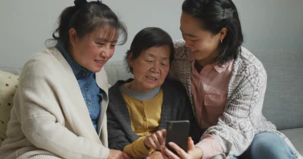 用智能手机与成年的女儿和孙女拥抱微笑着年长的亚洲女人 多代家庭 老年生活方式 团聚和幸福概念 — 图库视频影像