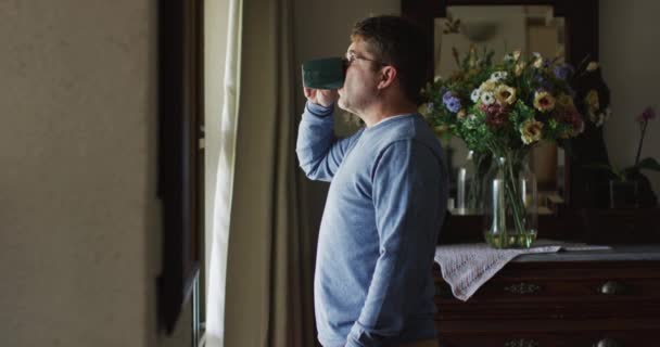 Przemyślany Biały Mężczyzna Stojący Przy Oknie Pijący Kawę Domu Koncepcja — Wideo stockowe