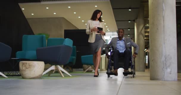 白人のビジネス女性とオフィスの車椅子でアフリカ系アメリカ人のビジネスマンを無効にします オフィスコンセプトのビジネス界やビジネス界では — ストック動画