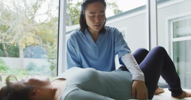 Asiatische Physiotherapeutin Behandelt Patientin Die Auf Dem Untersuchungsbett Der Praxis — Stockvideo