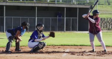 Çeşitli bayan beyzbol oyuncuları sahada oynuyor, atıcı topa vuruyor. Kadın beyzbol takımı, spor antrenmanı ve oyun taktikleri.