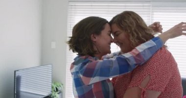 Beyaz lezbiyen çift oturma odasında sarılıp öpüşüyor. Ev hayatı, evde dinlenerek boş zaman geçirmek..