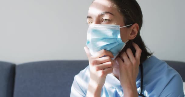 ソファに腰を下ろして顔のマスクをした白人女性医師 コロナウイルスにおける医療 医療サービス Covid 19パンデミック — ストック動画
