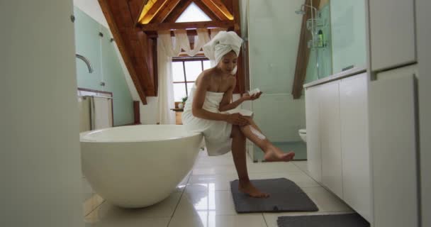 Mieszana Kobieta Rasy Nosząca Ręcznik Głowie Nakładająca Krem Nogi Życie — Wideo stockowe