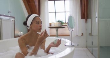 Karışık ırktan bir kadın güzellik maskesi takarak banyo yapıyor. ev hayatı, kaliteli boş zaman geçirmek evde dinlenmek..