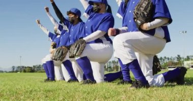 Yüz maskeli kadın beyzbol oyuncularından oluşan çeşitli takımlar kolları havada dizlerinin üzerinde dizlerinin üzerinde dizlerinin üstüne çöküyorlar. Coronavirus covid 19 salgını sırasında kadın beyzbol takımı, spor antrenmanı ve oyun..