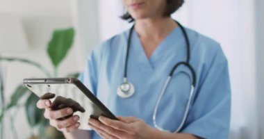 Evde tablet kullanan beyaz kadın doktor. Coronavirus covid 19 salgını sırasında ilaç, sağlık ve sağlık hizmetleri.