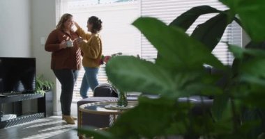 Kafkasyalı lezbiyen çift kucaklaşıp kahve içiyor. Ev hayatı, evde dinlenerek boş zaman geçirmek..