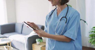 Evde tablet kullanan beyaz kadın doktor. Coronavirus covid 19 salgını sırasında ilaç, sağlık ve sağlık hizmetleri.