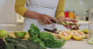 Sağlıklı içecek hazırlayan, meyve ve sebze kesen melez bir kadın. ev hayatı, kaliteli boş zaman geçirmek evde dinlenmek..