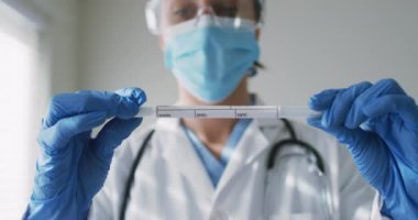 Beyaz kadın doktor, yüz maskesi takıyor ve test yaptırıyor. Coronavirus covid 19 salgını sırasında ilaç, sağlık ve sağlık hizmetleri.