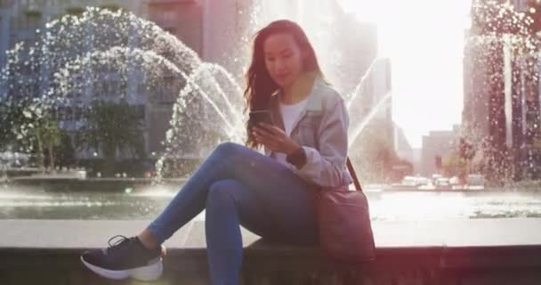 Asijská Žena Sedí Vedle Fontány Pomocí Smartphonu Pije Kávu Sebou — Stock video