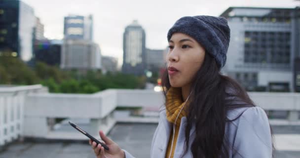 スマートフォンを使ってアジアの女性が歩いてサンドイッチを食べる 外にも街中にもデジタル ノマドが — ストック動画