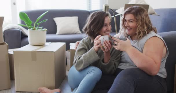 白人の幸せなレズビアンのカップルは 新しい家の床に座ってお茶を飲む 国内生活と余暇 — ストック動画