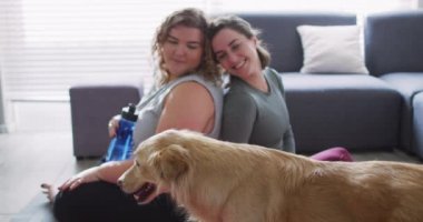 Kafkasyalı lezbiyen çift köpekle zinde ve dinleniyor. Ev hayatı, evde dinlenerek boş zaman geçirmek..