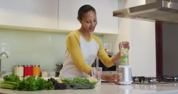 Смешанная Расовая Женщина Готовит Здоровый Напиток Смешивая Фрукты Овощи Кухне — стоковое видео