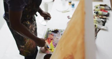 Sanatçı stüdyosunda boyaları karıştıran Afrikalı Amerikalı erkek ressamın orta bölümü. sanat, yaratıcı ve boş zaman kavramı.