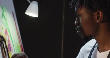 Sanat stüdyosunda, palet bıçağıyla resim yapan Afrikalı Amerikalı erkek sanatçıya yakın çekim. sanat, hobi ve yaratıcı meslek kavramı