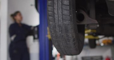 Kadın tamirci, otomatikman vinçle araba servisinin düğmesine basarak araba kaldırıyor. otomobil tamir servisi