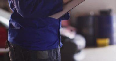 Kadın tamircinin orta bölümü bir araba servis istasyonundaki panoya not alıyor. otomobil tamir servisi
